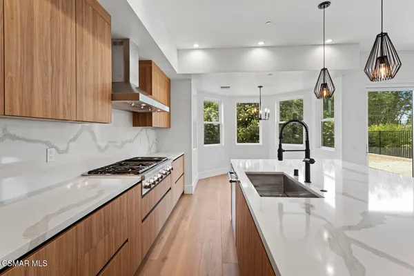 a kitchen with stainless steel appliances granite countertop a sink a stove and a wooden floors