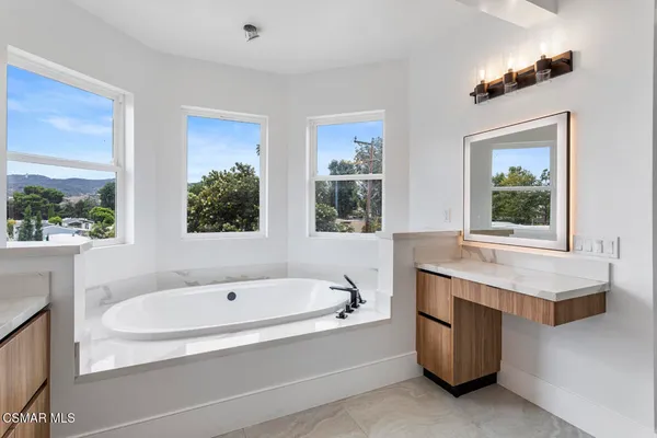 a bathroom with a tub sink and mirror