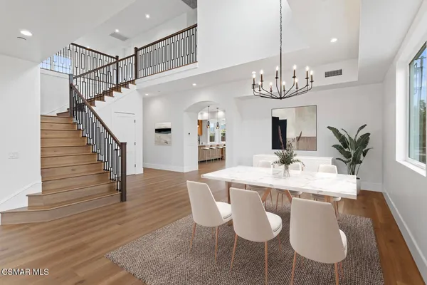 a dining room with wooden floor a chandelier a wooden table and chairs