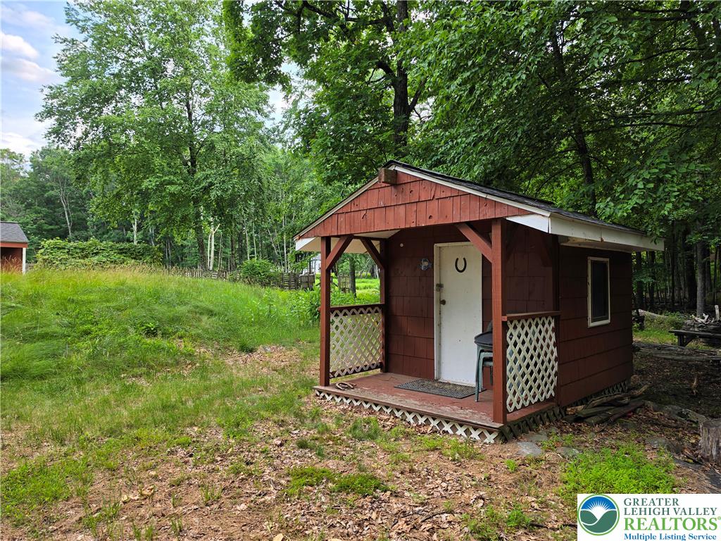 211 Murphy Circle Bushkill, PA 18324 - Photo 24 of 28 A charming rustic shed with a covered porch offers storage amidst the natural landscape.