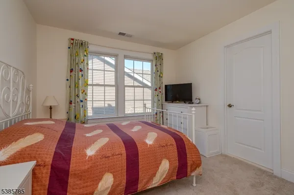 a bedroom with a bed flat screen tv and a window