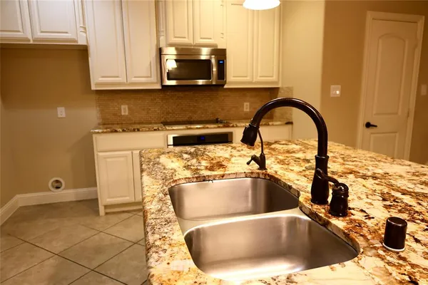 a kitchen with a sink a stove and white cabinets
