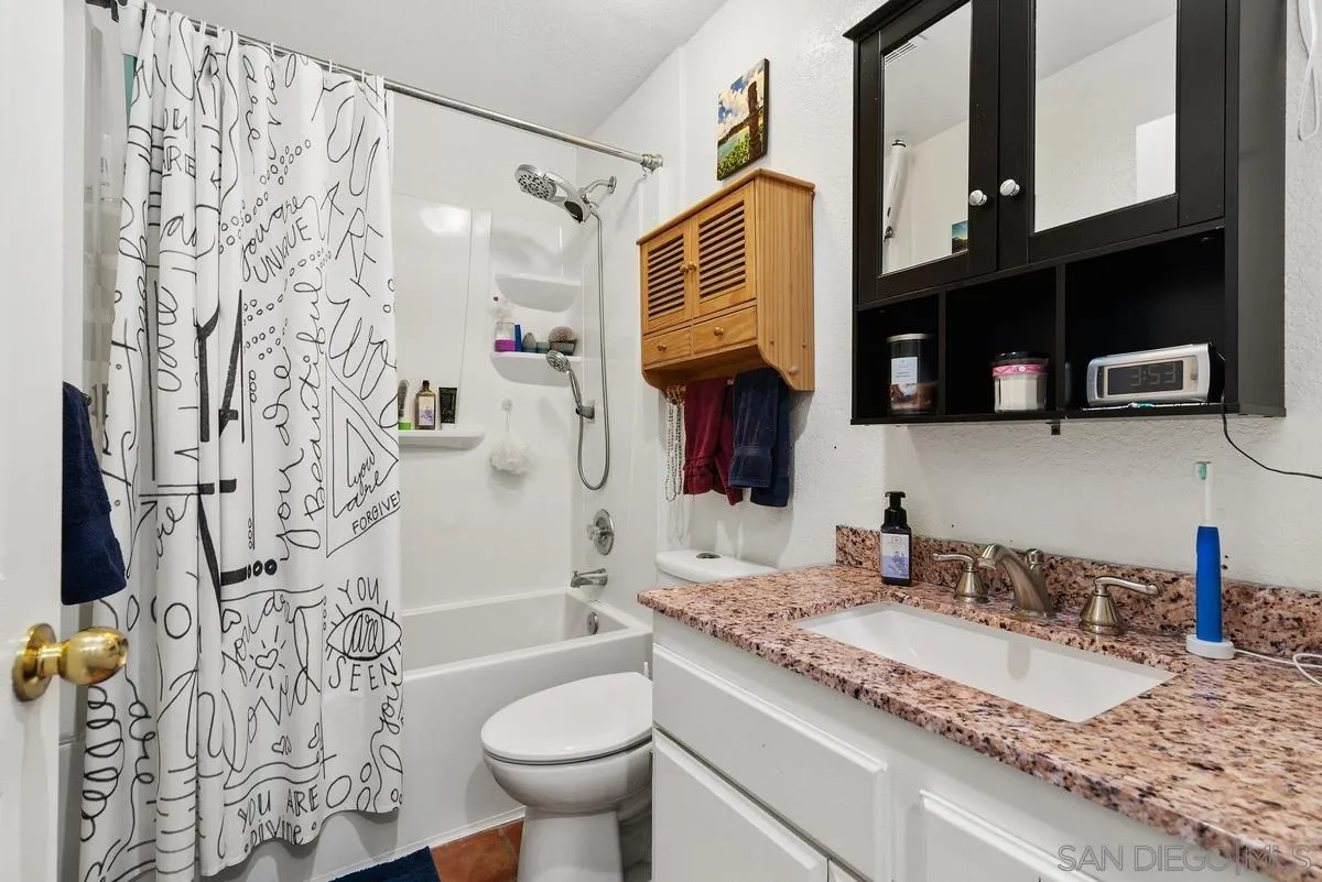 13975 Midland Road Poway, CA 92064 - Photo 22 of 33 a bathroom with a granite countertop sink a toilet and shower curtain