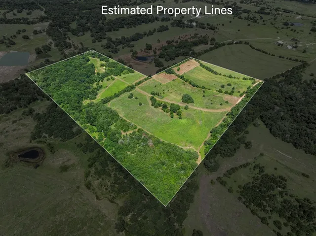 an aerial view of a residential houses with outdoor space and trees all around