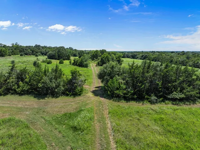 an aerial view of a houses with outdoor space and trees all around