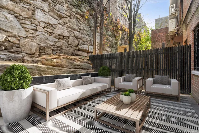 a view of a patio with couches and a fire pit and wooden fence