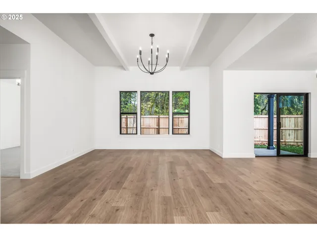 a view of an empty room with wooden floor and window