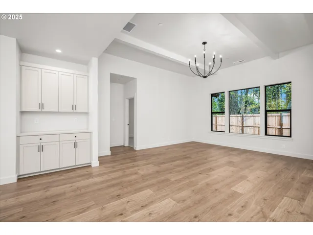 a view of an empty room with window wooden floor and kitchen view