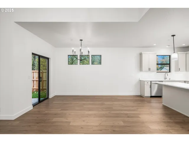 a view of an empty room with kitchen and window