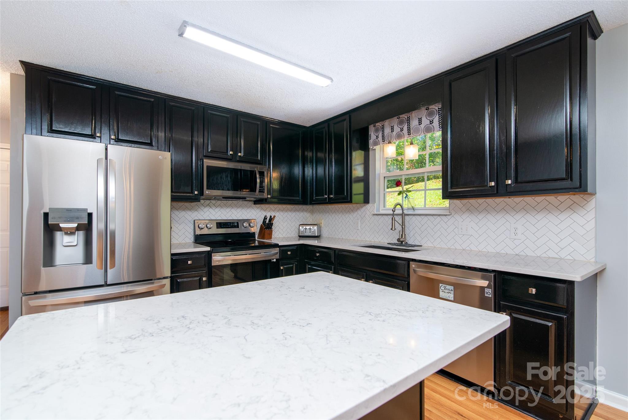 32 Wheat Ridge Road Sylva, NC 28779 - Photo 22 of 44 a kitchen with granite countertop a refrigerator a sink a stove a microwave and wooden cabinets
