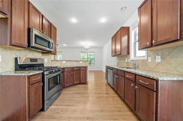 a large kitchen with stainless steel appliances granite countertop wooden cabinets a sink and a stove