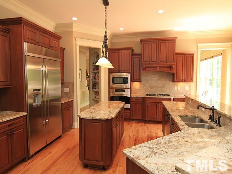 1305 Mason Road Durham, NC 27712 - Photo 11 of 25 a kitchen with stainless steel appliances kitchen island granite countertop a refrigerator a sink and wooden cabinets