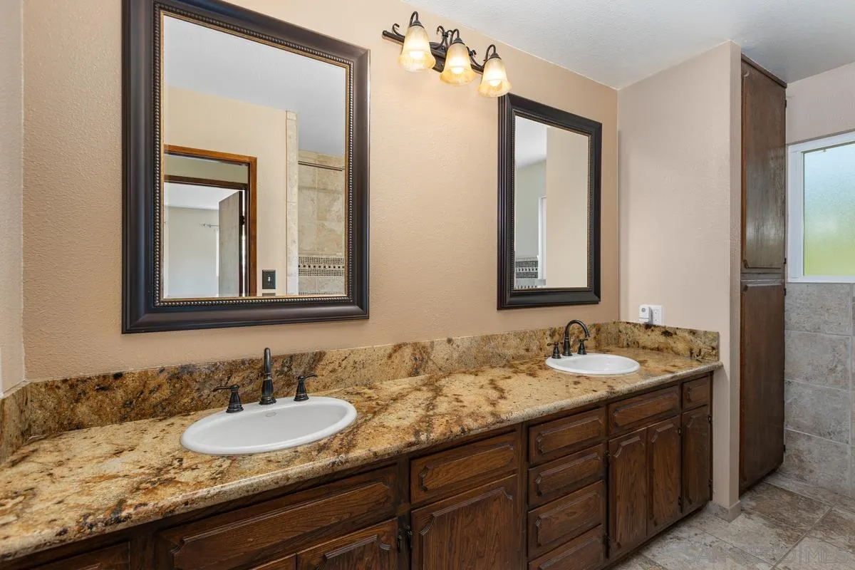 3049 Millar Ranch Road Spring Valley, CA 91978 - Photo 47 of 71 a bathroom with a granite countertop sink and a mirror