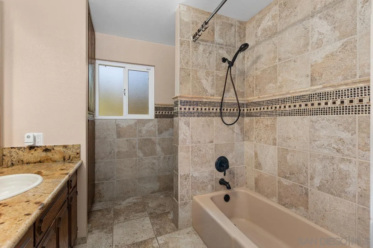 3049 Millar Ranch Road Spring Valley, CA 91978 - Photo 48 of 71 a bathroom with a granite countertop sink a mirror a shower and bathtub