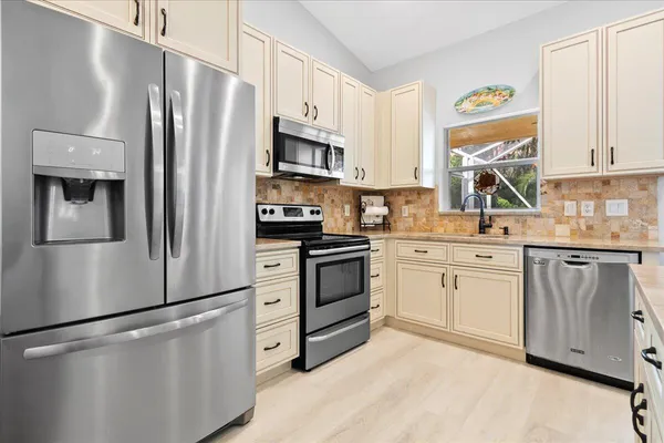 a kitchen with stainless steel appliances a refrigerator sink and white cabinets