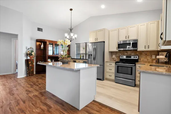 a kitchen with stainless steel appliances kitchen island granite countertop a refrigerator stove and sink