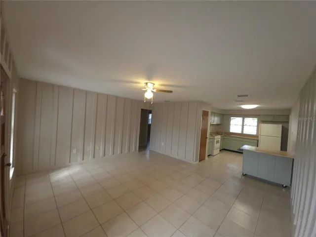 an empty room with a kitchen and natural light