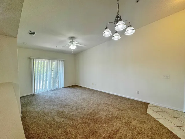 a view of an empty room with a chandelier fan