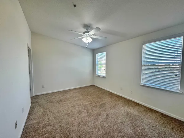 an empty room with windows and fan