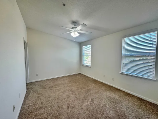 an empty room with windows and fan
