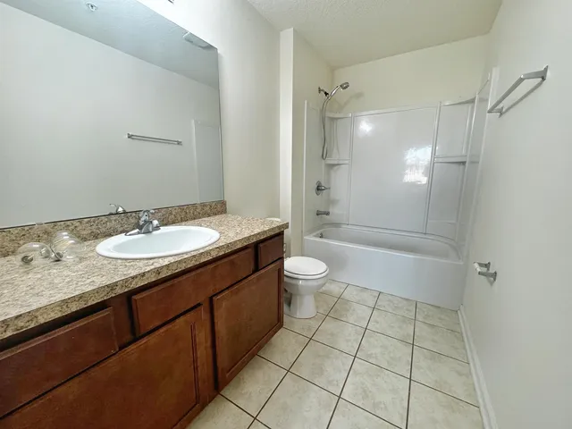 a bathroom with a granite countertop sink a toilet a mirror and shower
