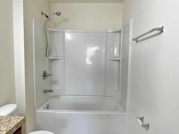 a bathroom with a granite countertop bathtub shower and toilet