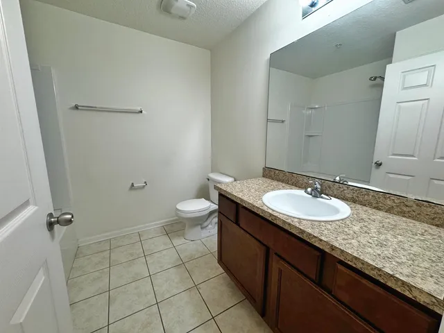 a bathroom with a granite countertop sink a toilet and a mirror