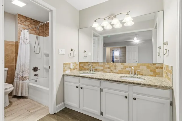 a bathroom with a granite countertop sink a toilet and a large mirror