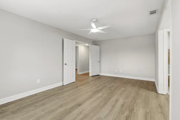an empty room with wooden floor and windows