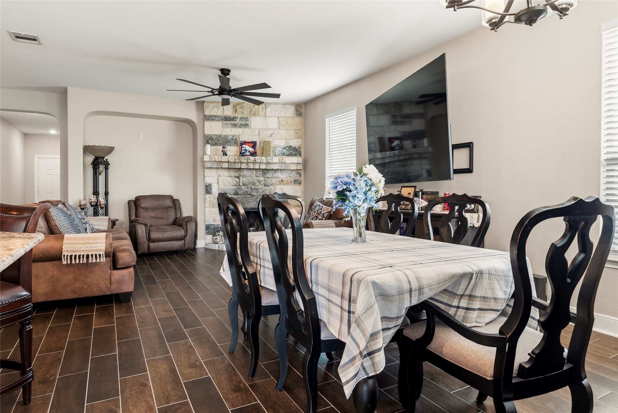 105 West Point Way Elgin, TX 78621 - Photo 22 of 27 Open concept living and dining area featuring wood-finish flooring, a stone-faced fireplace, and a ceiling fan