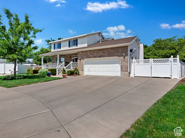 View of front of property featuring a garage, a front lawn, and a porch