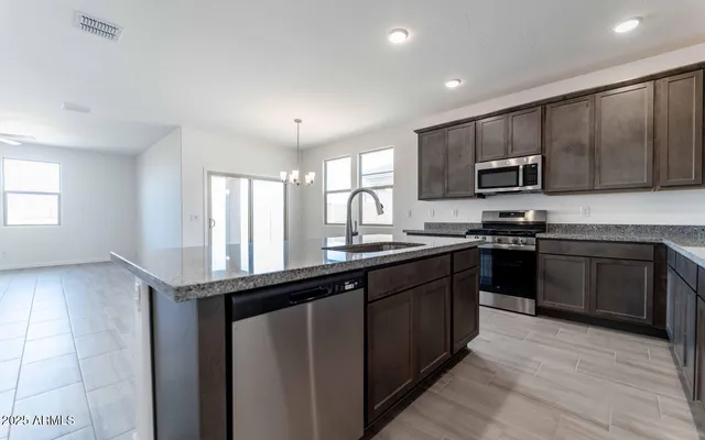 a kitchen with kitchen island granite countertop a sink wooden cabinets and stainless steel appliances