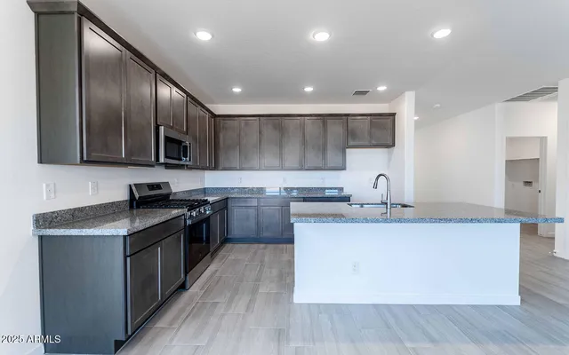 a kitchen with stainless steel appliances granite countertop a sink a stove top oven and wooden floors