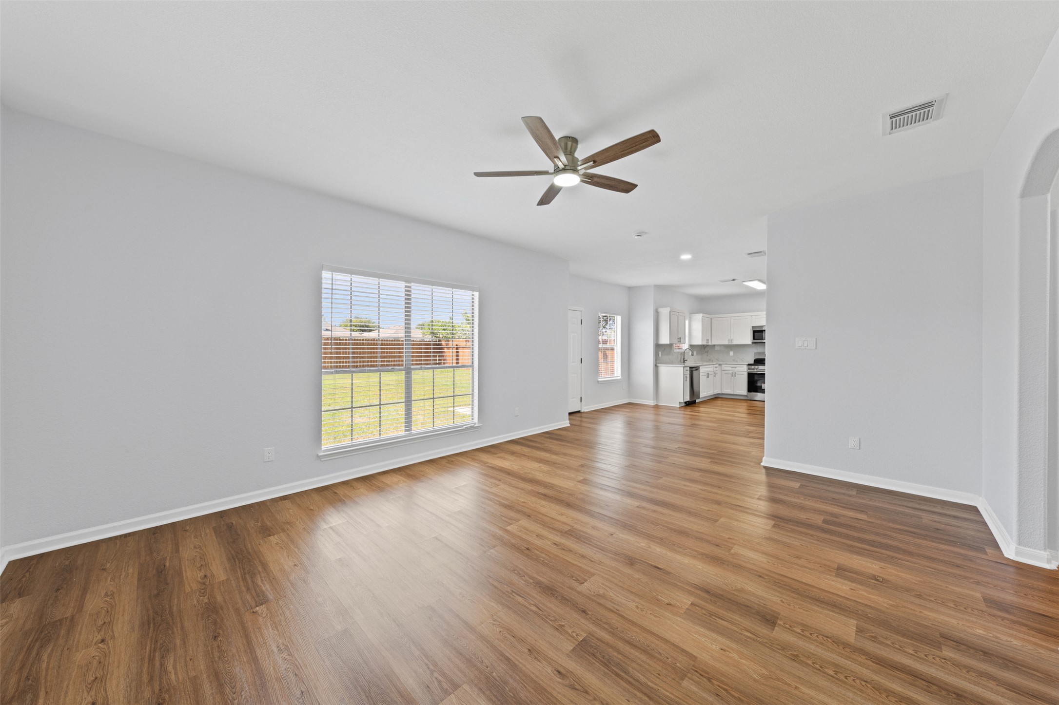 243 Engineers Pass Jarrell, TX 76537 - Photo 15 of 40 Spacious room featuring wood-finish flooring, a ceiling fan with integrated lighting, and a large window with horizontal blinds overlooking a grassy yard