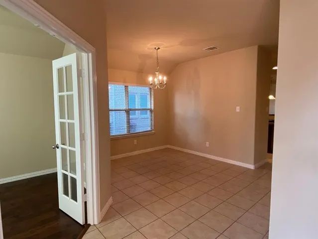 an empty room with wooden floor mirror and windows