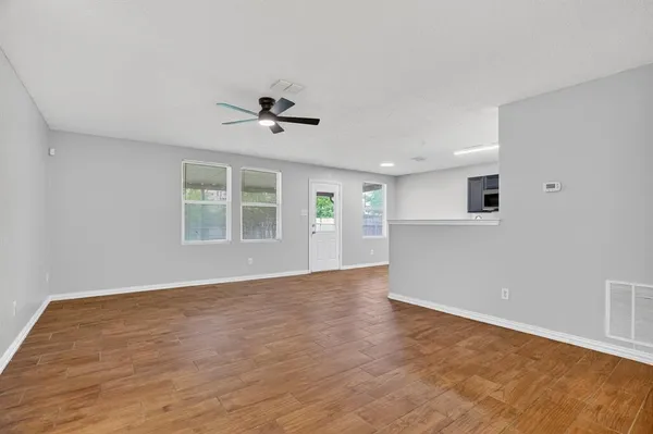 a view of an empty room with a window and wooden floor