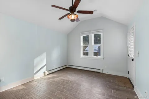 an empty room with wooden floor ceiling fan and windows