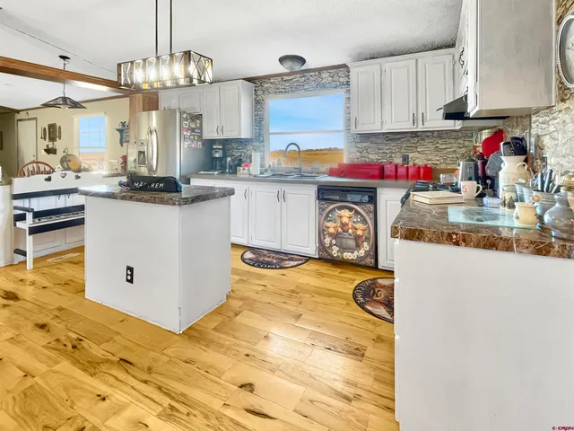 a view of an empty room with wooden floor and a ceiling fan
