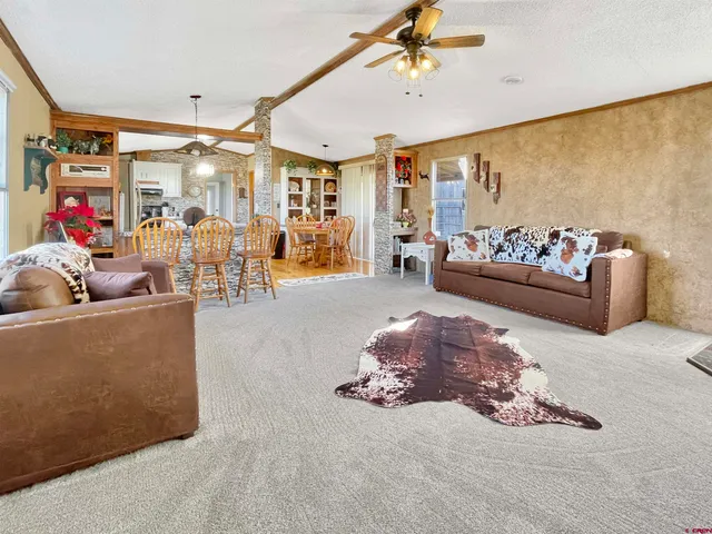 a view of a dining room with furniture a chandelier and kitchen view