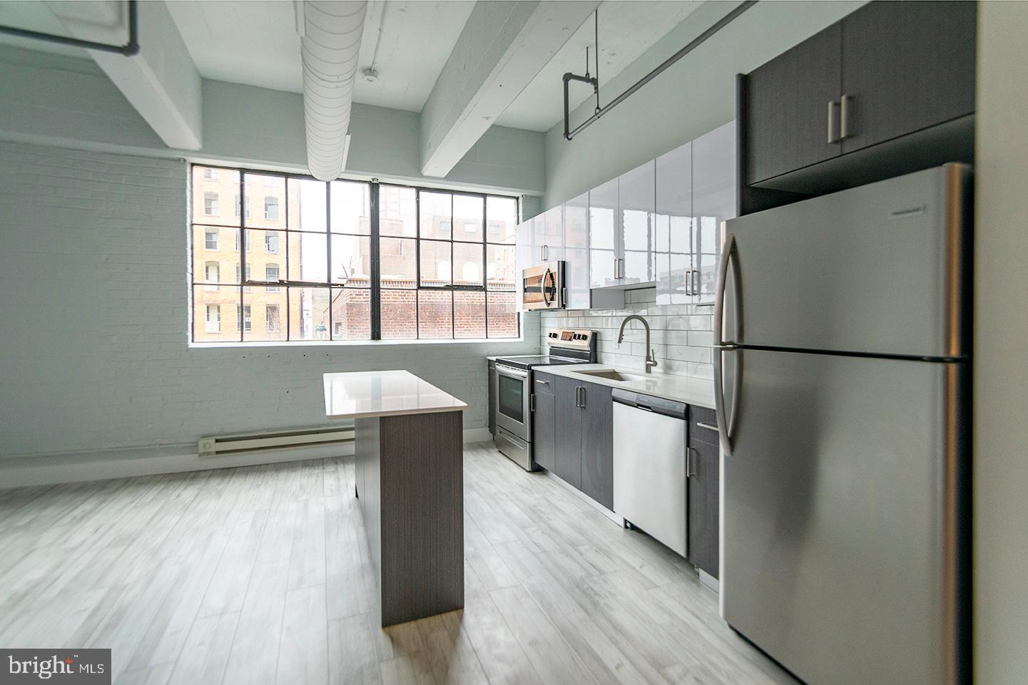 a kitchen with a sink a refrigerator and wooden floor