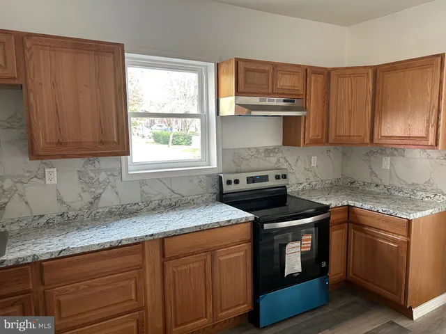 a kitchen with granite countertop wooden cabinets appliances and a window