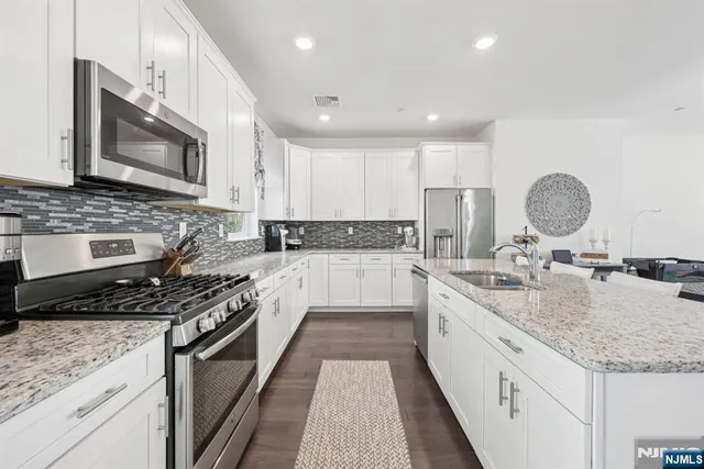 a large kitchen with granite countertop a sink and a stove