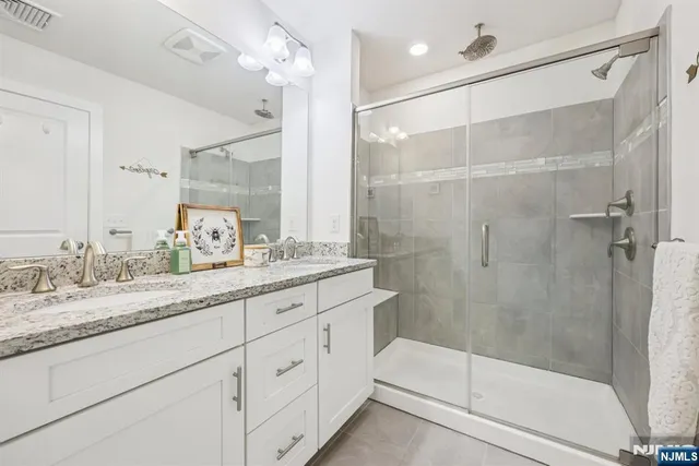 a bathroom with a granite countertop sink a mirror a shower and a bathtub