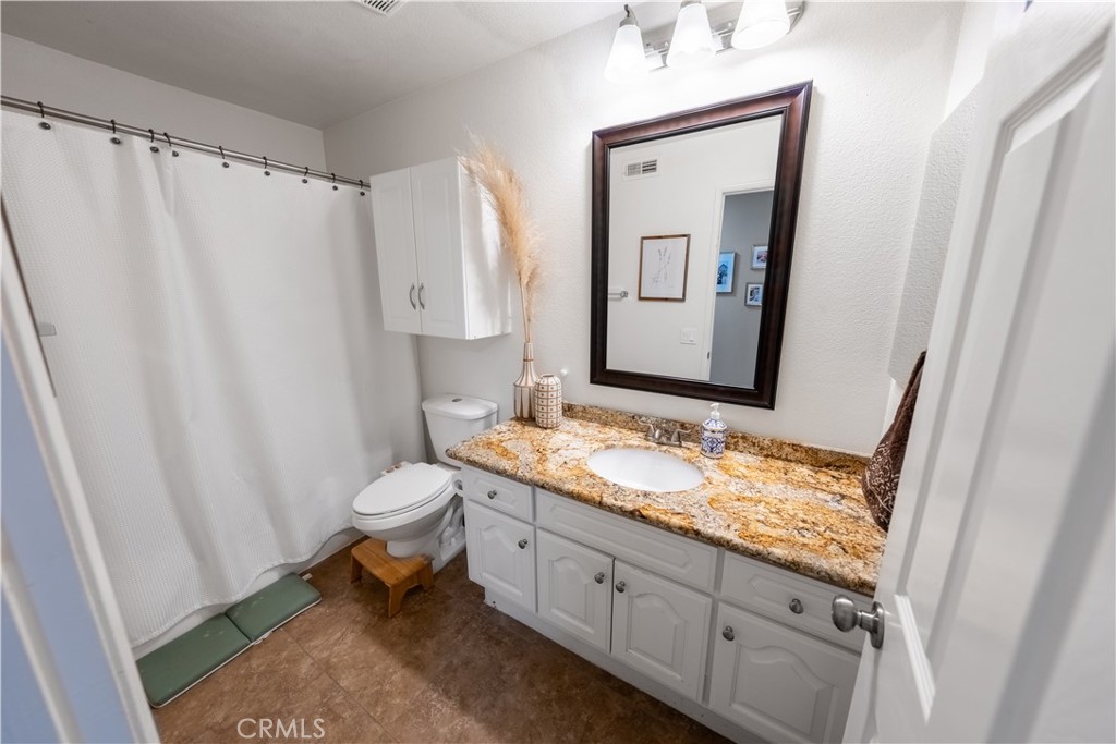 10451 Morning Ridge Drive Moreno Valley, CA 92557 - Photo 52 of 56 a bathroom with a granite countertop sink toilet and mirror