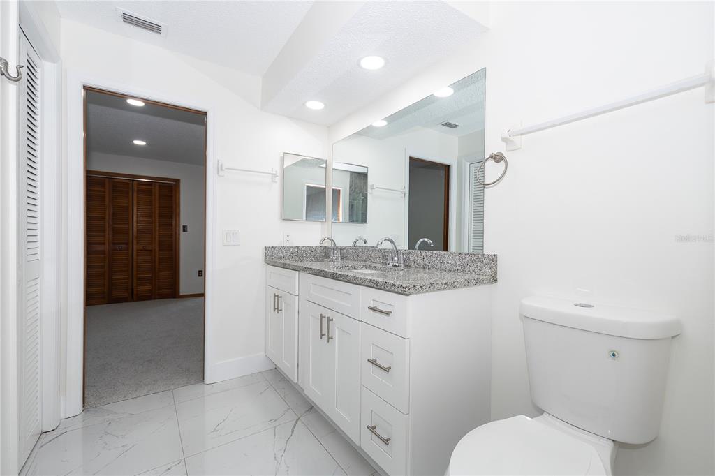 8557 Pilgrim Court New Port Richey, FL 34653 - Photo 22 of 29 a bathroom with a granite countertop toilet sink and mirror