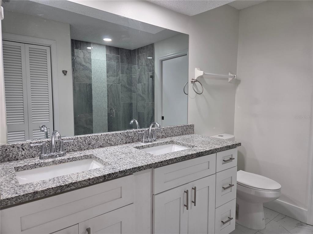 8557 Pilgrim Court New Port Richey, FL 34653 - Photo 24 of 29 a bathroom with a granite countertop sink a toilet and a mirror