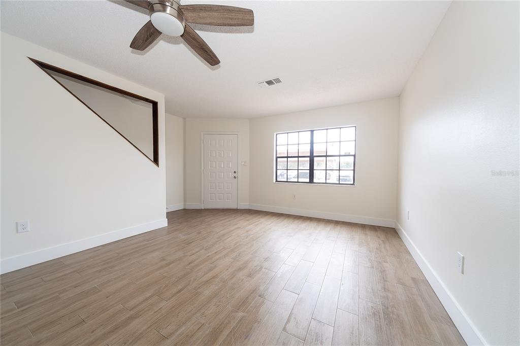 8557 Pilgrim Court New Port Richey, FL 34653 - Photo 4 of 29 an empty room with wooden floor chandelier fan and windows