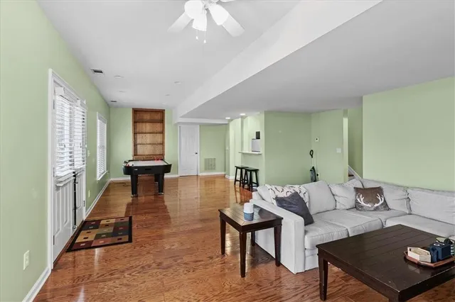 a living room with furniture a ceiling fan and a large window