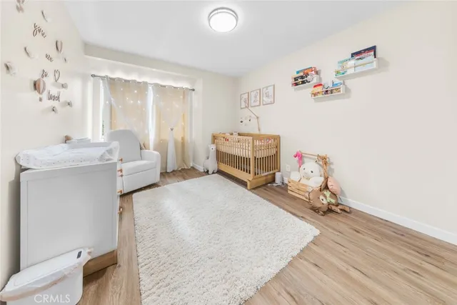 a room with a baby bed a couch and a window