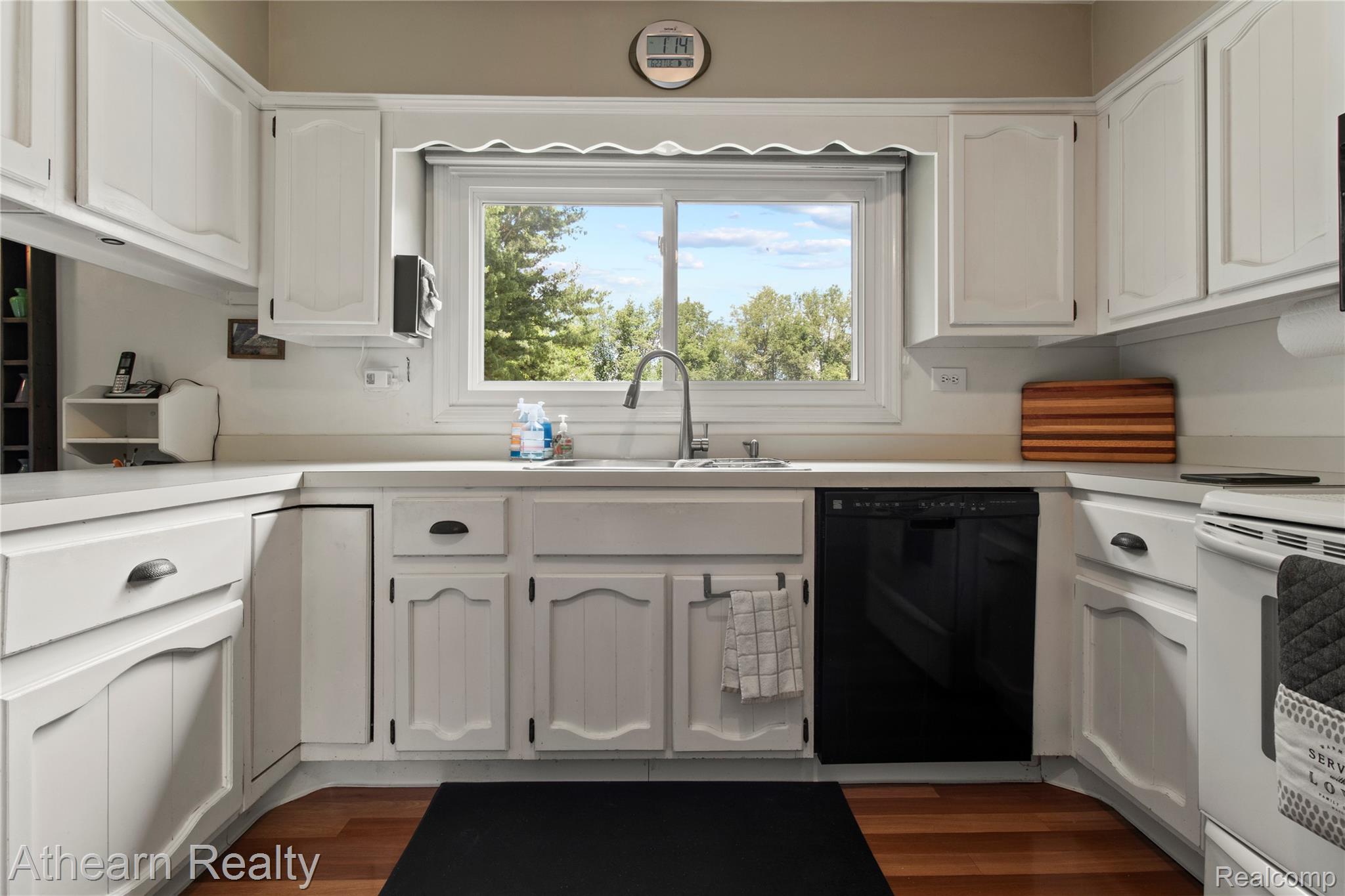 12427 Foley Road Fenton, MI 48430 - Photo 25 of 47 Kitchen featuring white cabinetry, wood-finish flooring, a stainless steel sink with a gooseneck faucet, a black dishwasher, and a white stove